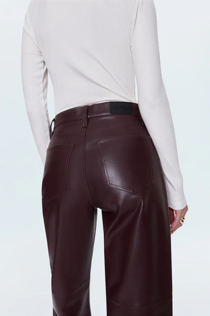Merlot leather pants worn by a person on a light blue background