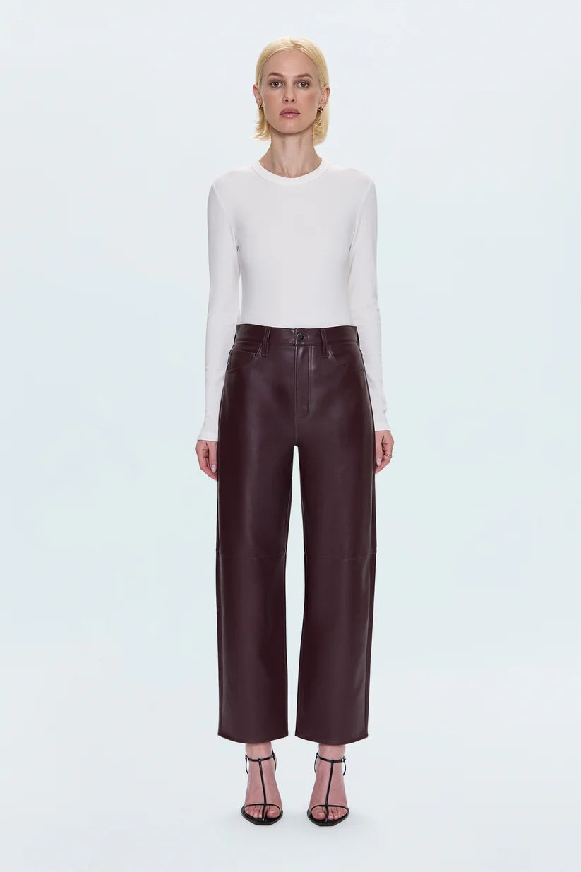 Merlot leather pants worn by a person on a light blue background