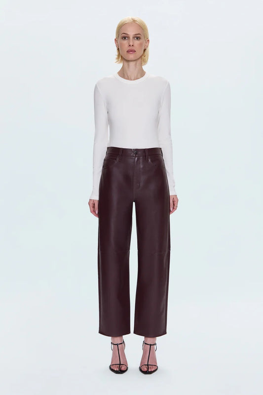 Merlot leather pants worn by a person on a light blue background