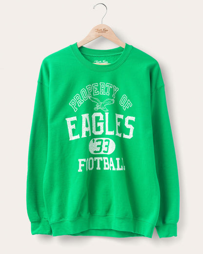 Eagles sweatshirt hanging on hanger showing front that says "property of eagles football" on a white background