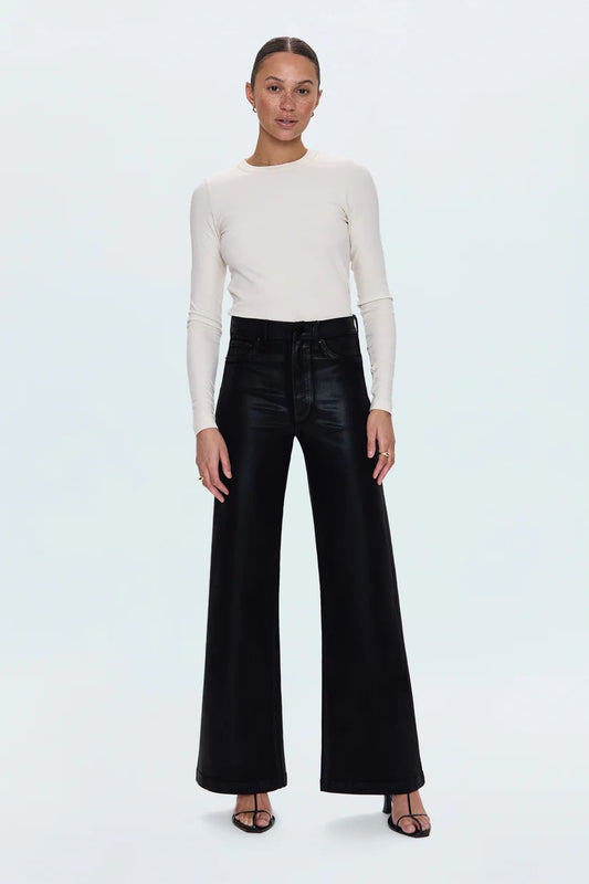 Woman wearing a white long-sleeve top and black high-waisted pants on a light gray background