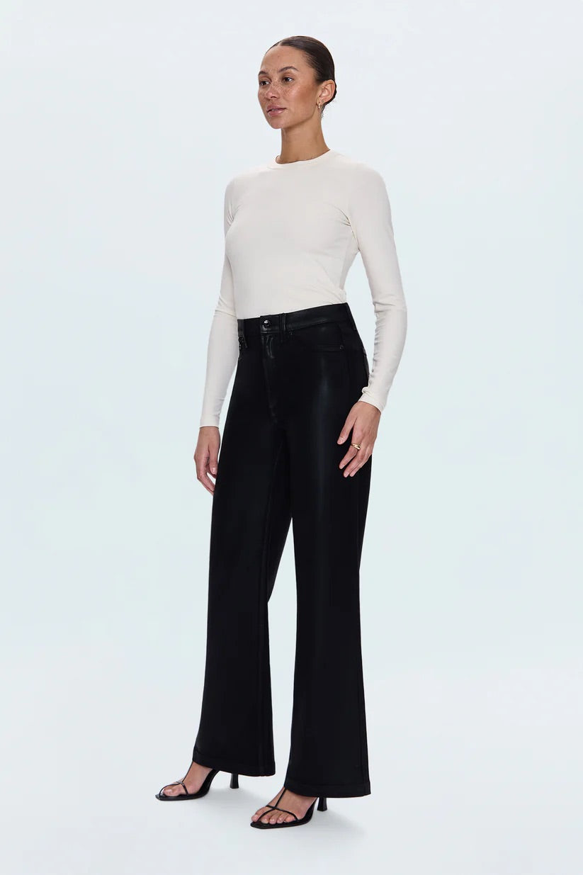 Woman wearing a white long-sleeve top and black high-waisted pants on a light gray background