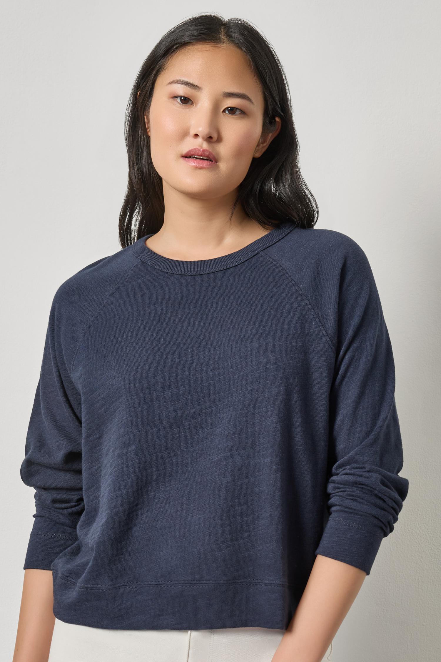 Woman wearing a navy blue sweater against a plain background