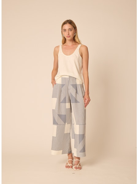 Woman wearing a sleeveless top and patterned pants on a beige background