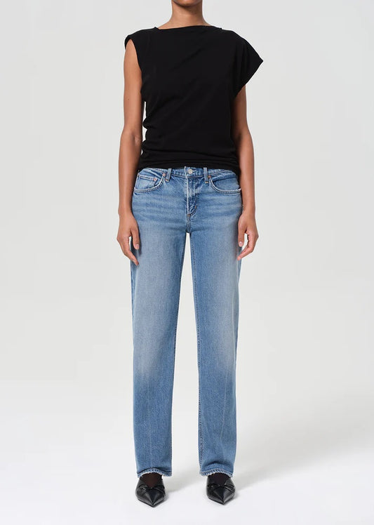 Person wearing a black sleeveless top and blue jeans on a white background