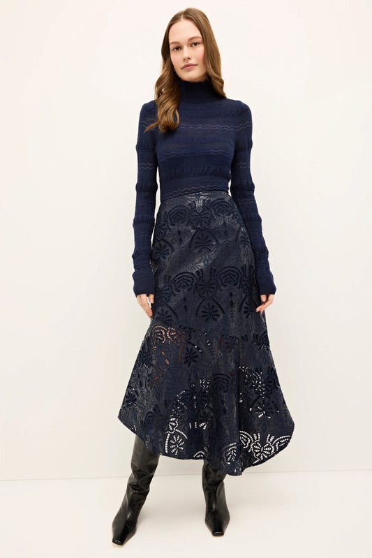 Woman wearing a navy blue top and patterned skirt on a white background