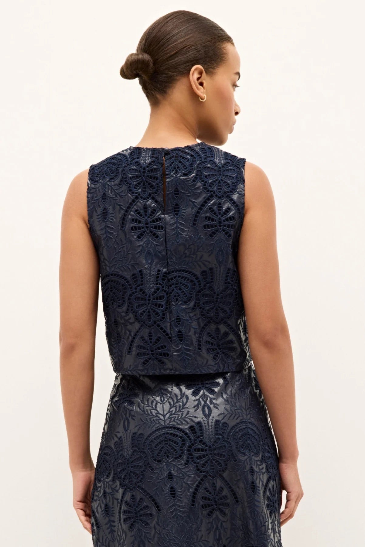 Woman wearing a navy blue lace dress against a white background