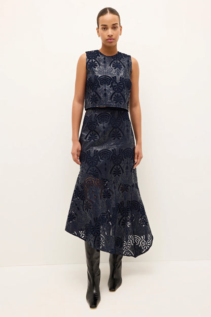 Woman wearing a dark blue embroidered dress with a white background