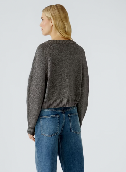 Person wearing a gray sweater and blue jeans on a light gray background