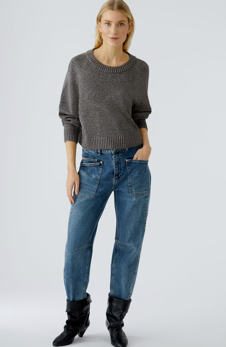 Woman wearing a gray sweater and blue jeans on a white background