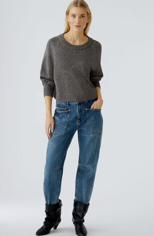 Woman wearing a gray sweater and blue jeans on a white background