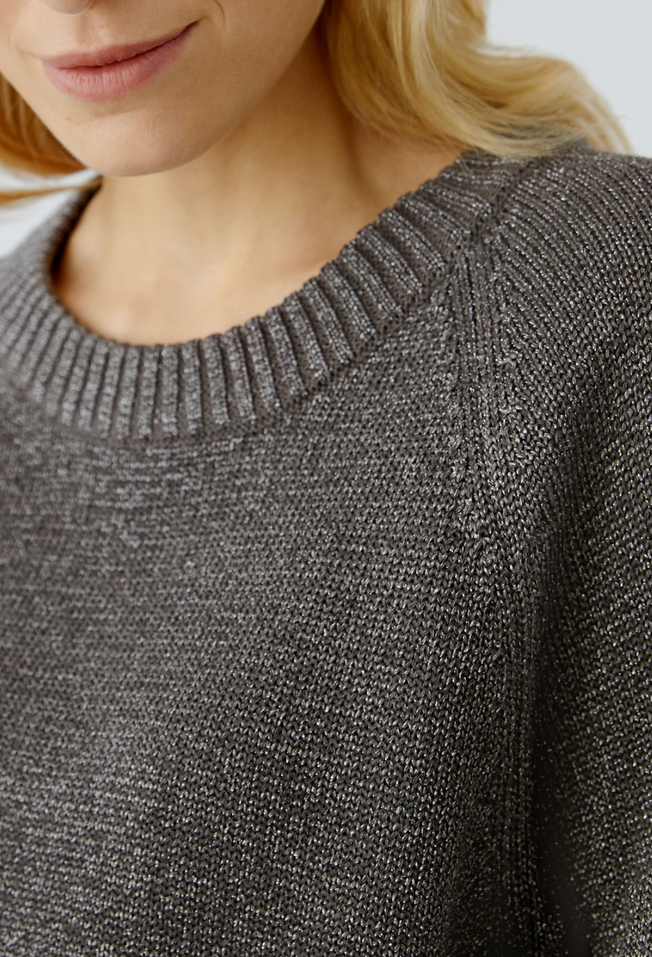 Close-up of a person wearing a gray textured sweater