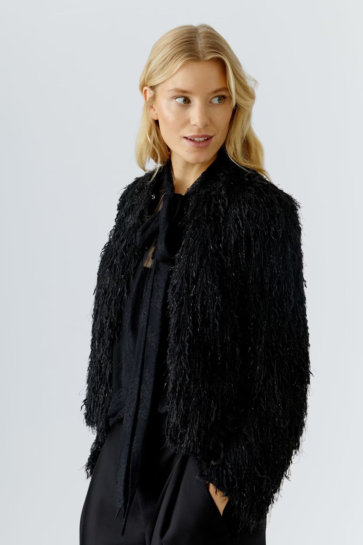 Woman wearing a black shaggy jacket against a light gray background