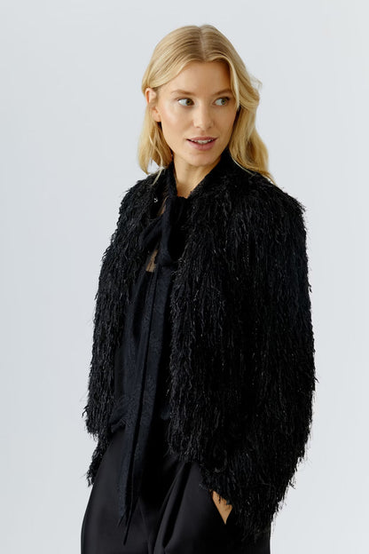Woman wearing a black shaggy jacket against a light gray background