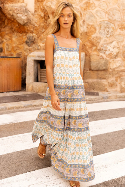 Woman wearing a patterned dress standing on a street with a stone building in the background