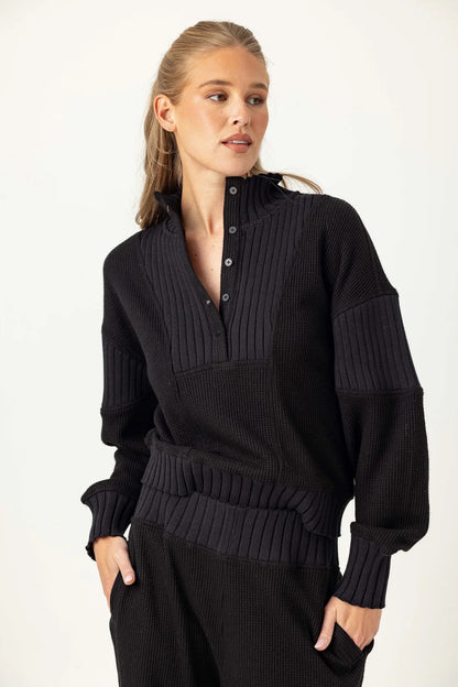 Woman wearing a black ribbed sweater and pants on a white background