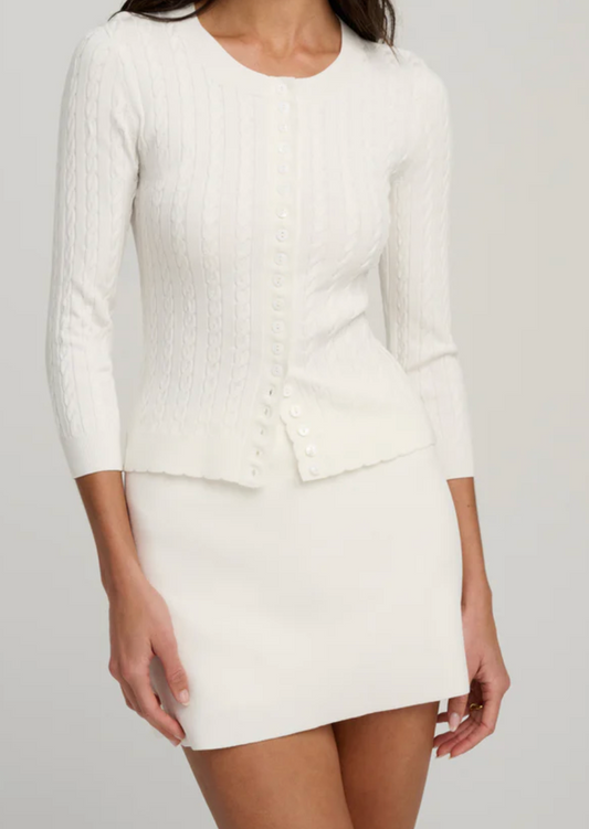 Person wearing a white sweater and skirt on a plain background