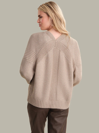 Woman wearing a beige sweater with a neutral background