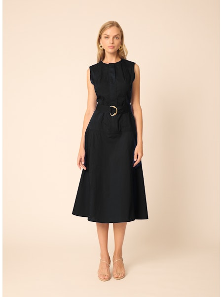 Woman wearing a black sleeveless dress with a belt on a beige background