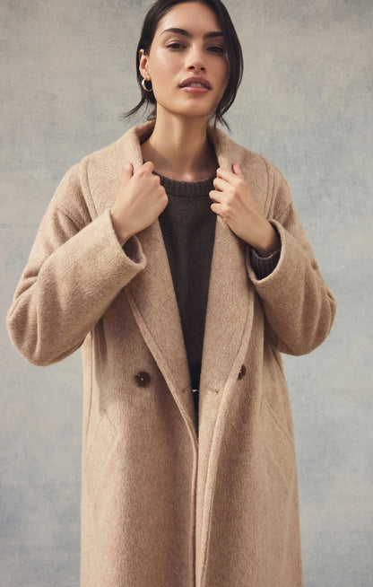 Woman wearing a beige coat against a plain background