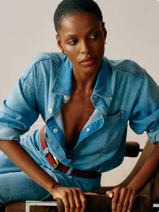 Woman wearing a blue denim outfit sitting on a chair.