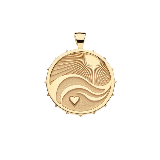 A round gold pendant featuring an engraved sunburst, flowing wave lines, and a small heart, shown on a plain white background.