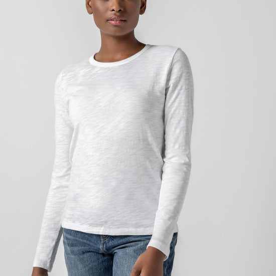 Person wearing a white long-sleeve shirt and blue jeans on a light gray background