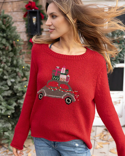 Woman wearing a red sweater with a Christmas tree and presents design, standing outdoors.