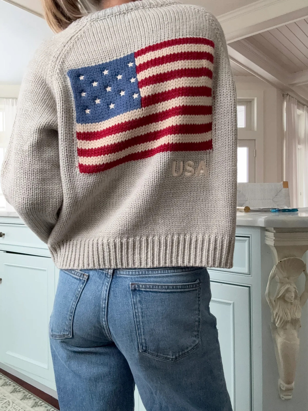 Person wearing a sweater with an American flag design in a kitchen setting