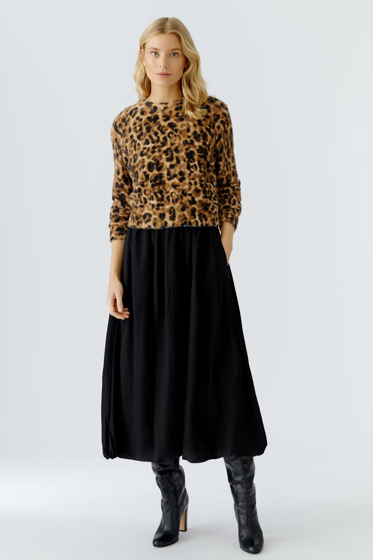 Woman wearing a leopard print sweater and black skirt on a white background