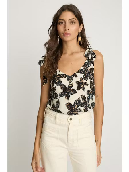 Woman wearing a sleeveless top with black floral pattern on a white background