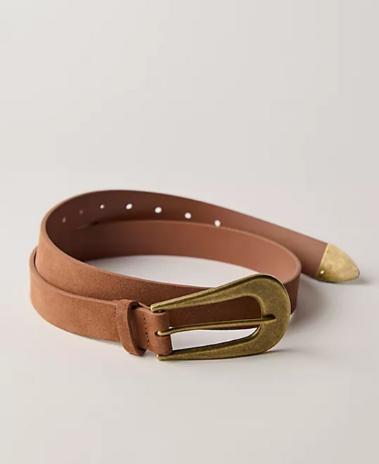 A tan leather belt with a gold-toned metal buckle and a gold-toned tip, coiled on a light gray background.