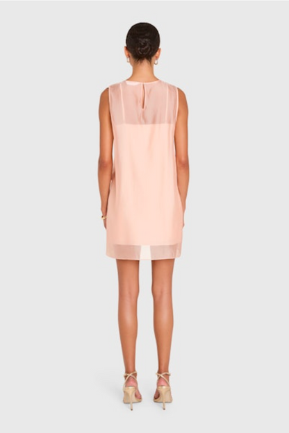 Woman wearing a light pink sleeveless dress on a white background