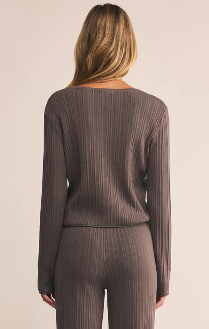 Woman wearing a brown ribbed long-sleeve top and pants on a beige background