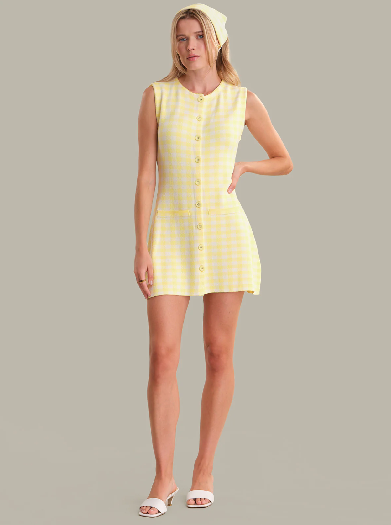 Woman wearing a yellow checkered dress against a gray background