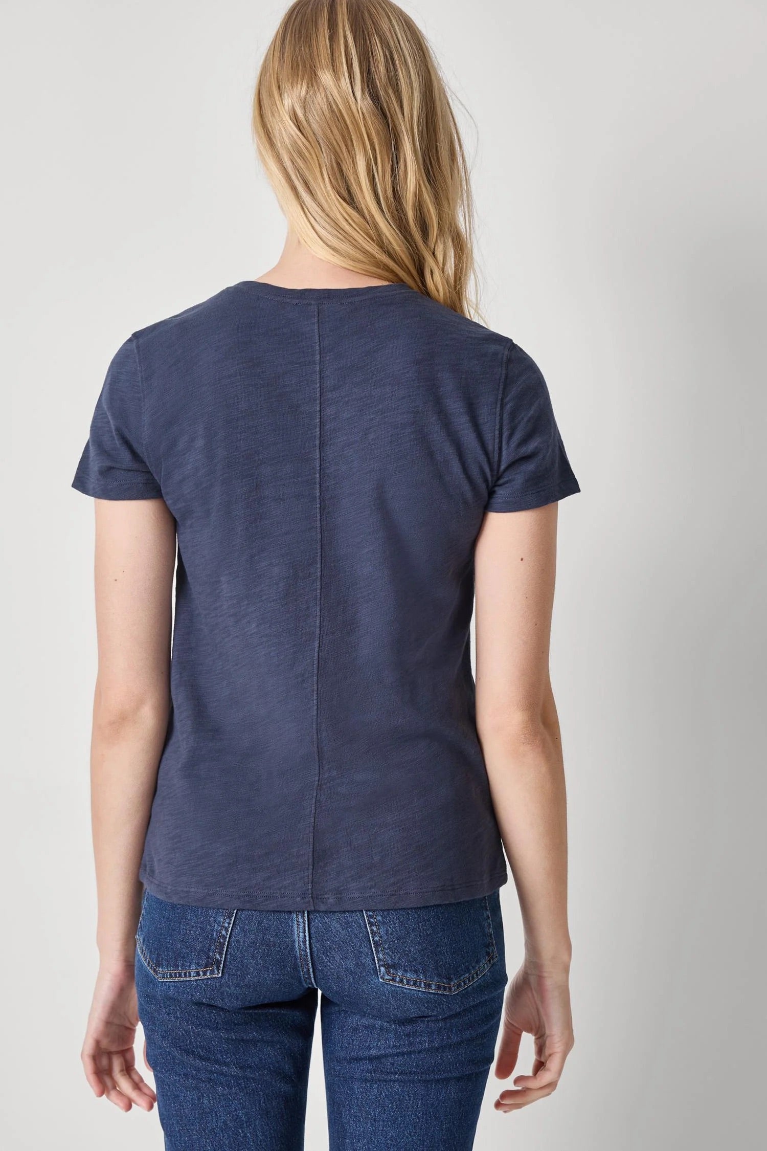 Person wearing a blue t-shirt and jeans on a plain background