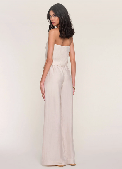 Woman wearing a strapless beige jumpsuit on a plain background