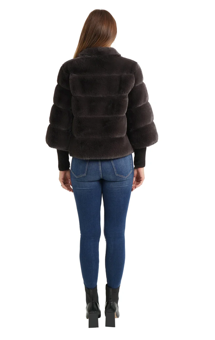 Person wearing a dark brown fur jacket and blue jeans on a white background