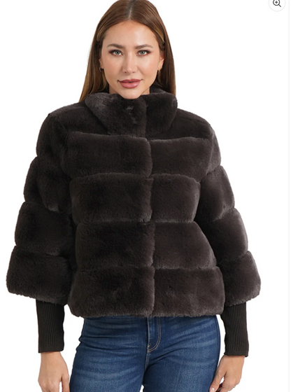 Woman wearing a dark brown faux fur jacket on a white background