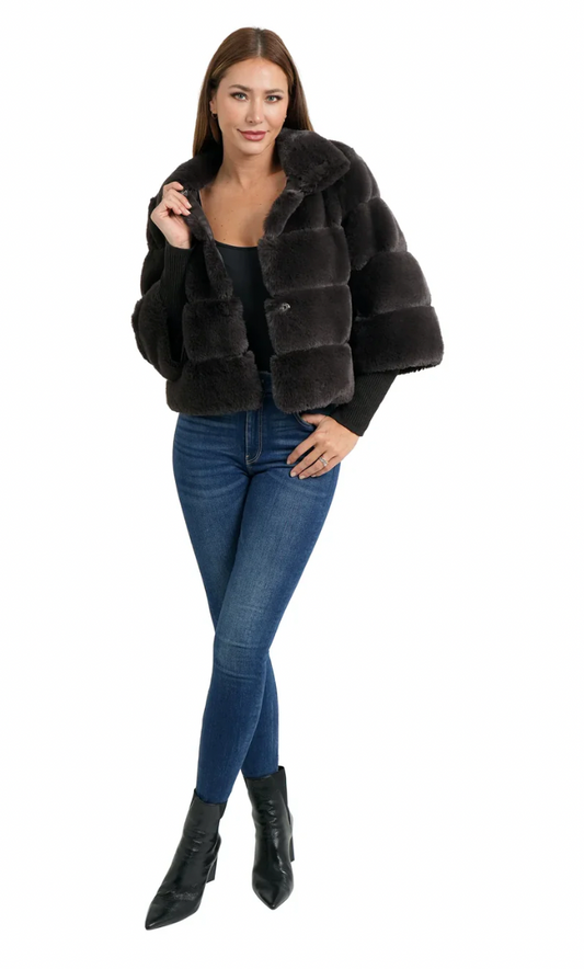 Woman wearing a dark fur coat, black top, blue jeans, and black boots on a white background