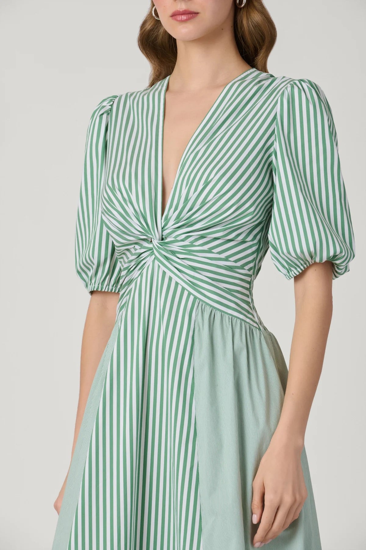 Green and white striped dress with puff sleeves on a plain background
