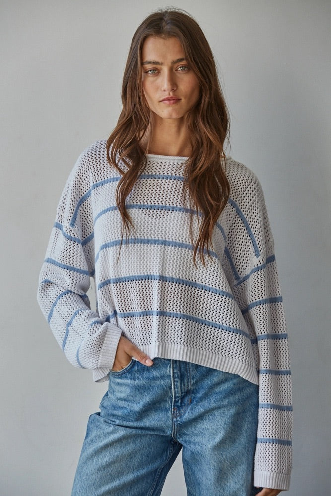 Woman wearing a striped sweater and jeans against a gray background
