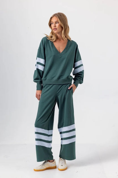 Woman wearing a green tracksuit with white stripes on a white background