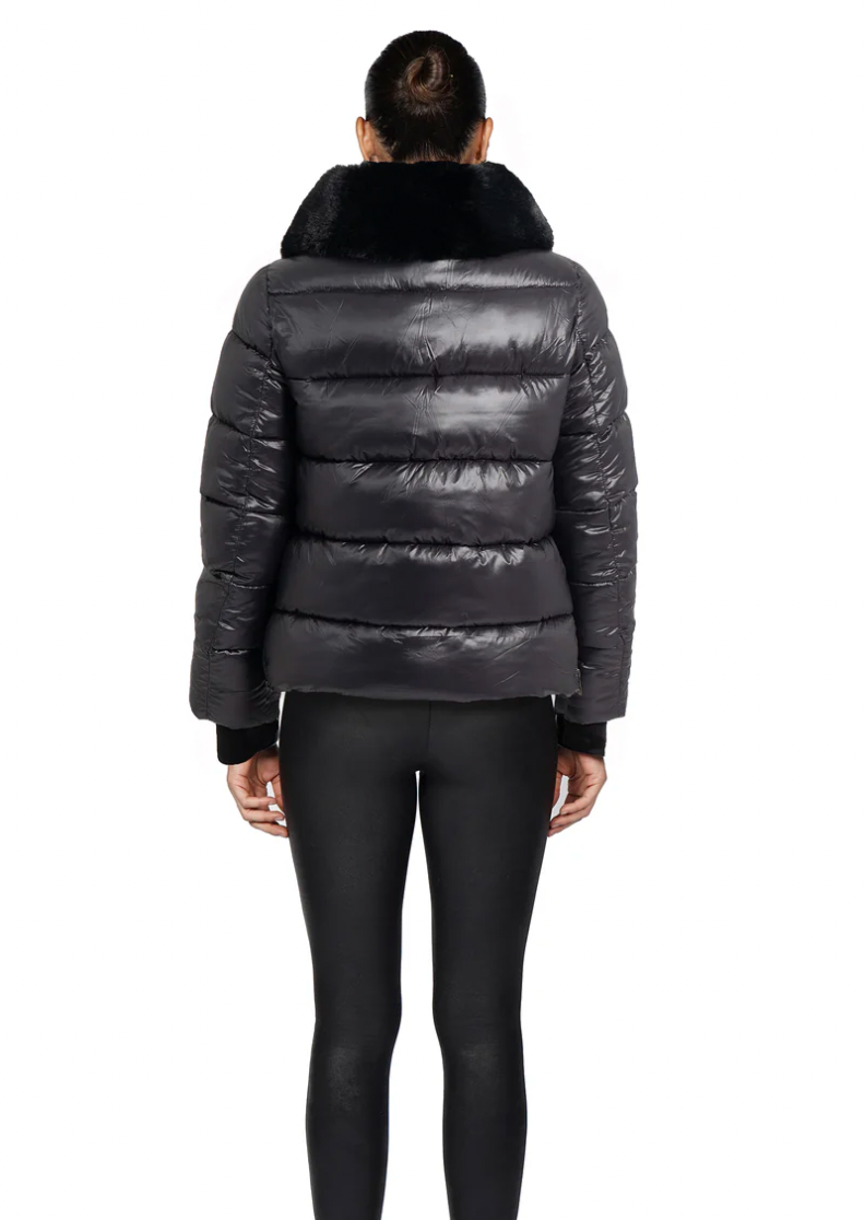 Person wearing a black puffer jacket with fur hood on a white background