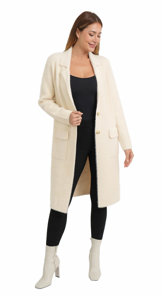 Woman wearing a long cream coat over a black outfit on a white background