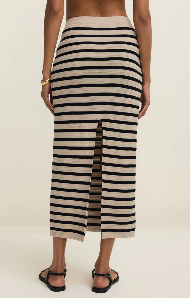 Person wearing a black and white striped skirt on a plain background